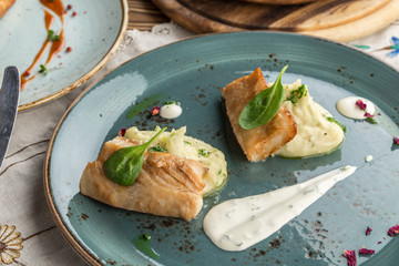 Pan fried trout with mashed potatoes on blue plate on wooden table