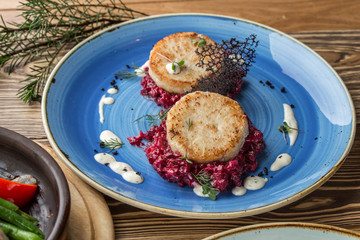 fried fish rissole served with beetroot on blue plate on wooden table