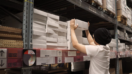 Warehouse large storage or cargo for distribution and man is picking up a box.