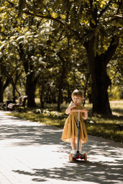 Little Young Girl Riding her Scooter in Park