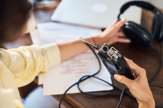 Crop woman making recordings over table