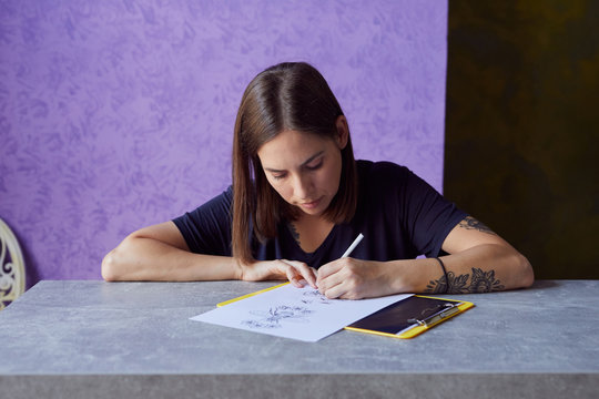 Young woman drawing a tattoo on the paper.