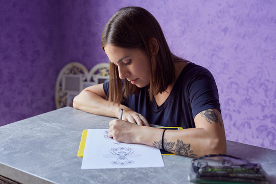 Young woman drawing a tattoo on the paper.