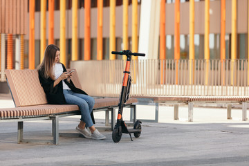 Woman doing a break in the square with her rented electric scooter