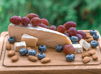 Set of elite delicious food, Brie cheese, grape, migdal and blueberry