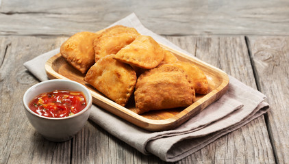 Typical Colombian empanadas served with spicy sauce on wooden surface