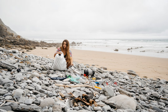 Young girl picking up plastic waste from beach