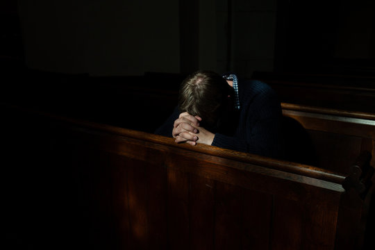 Man bows his head in prayer in Church.
