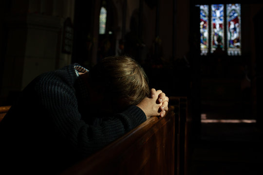 Man bows his head in prayer in Church.