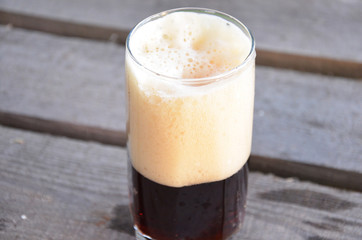 Glass of dark beer on the wooden background