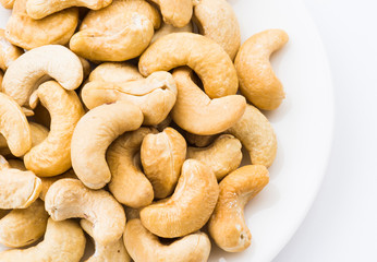 fresh cashew nuts on a white dish above the white background