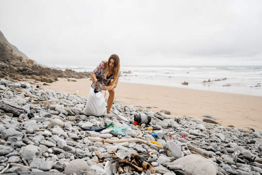 Young girl picking up plastic waste from beach