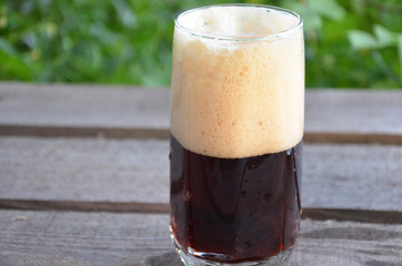Glass of dark beer on the wooden background