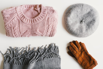 Flat lay with handmade knitted sweater, beret hat, woolen scarf and suede gloves on white...