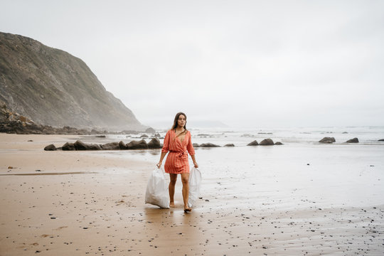 Young girl picking up plastic waste from beach