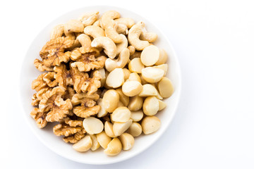 Variety of fresh nuts on a white dish above the white background