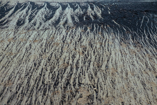Two different colours of sand draw rhythmic and mesmerising shapes on the beach