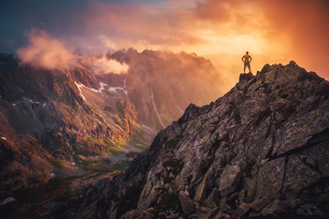 Hiker on the top of the hill looking at beautiful sunset sky. Silhouette of young hiker, edit space. Travel, adventure or expedition concept.