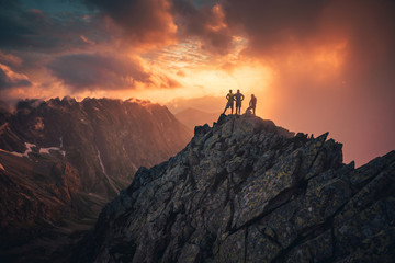 Group of people on mountain top against sunset lakes and mountains. Travel, adventure or expedition concept..