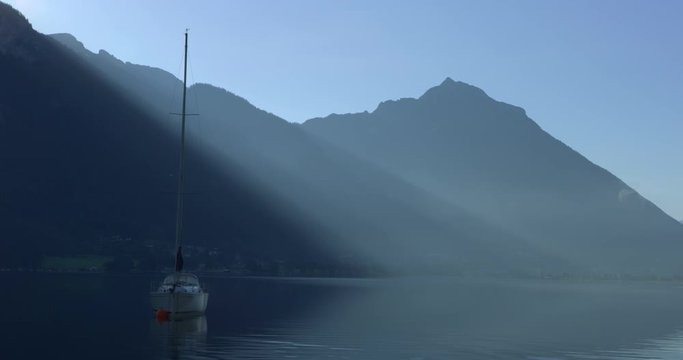 Panning Left shot, Boat on the Aschensee lake, scenic view of mountain range mist and bright sky in the background.