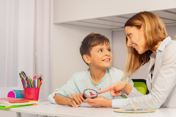 Boy with autism spectrum disorder during ABA therapy look at teacher pointing to lesson timer...