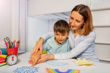 Boy with autism learn weather using cards, teacher hold hands and point to correct one - obrazy, fototapety, plakaty