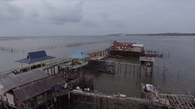 Flypass Drone shot of a rural fishing village hut off the coast on a gloomy day - 30fps