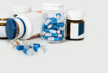 Blue pills in glass and plastic bottles on white background, health care concept.