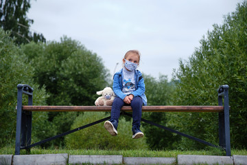 Little girl in a medical mask with her toy