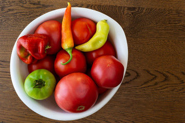 A bowl of tomatoes and peppers on wooden table