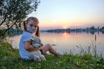 Little girl in a medical mask with her toy