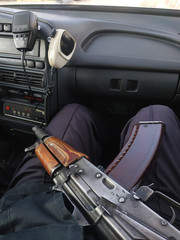 A Kalashnikov assault rifle lies on the lap of a policeman.