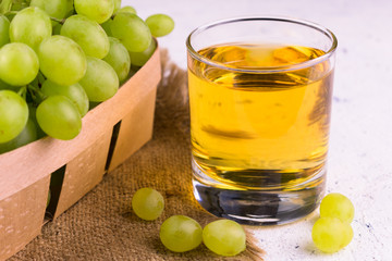 
Glass with grape juice and a bunch of grapes on a white background.