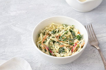 Homemade healthy coleslaw salad with kale in white bowl on gray textured background, top view, space