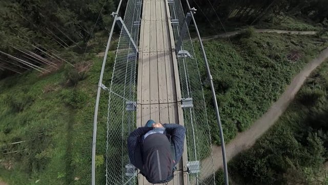 Mann l&auml;uft &uuml;ber eine H&auml;ngeseilbr&uuml;cke, Geierlay im Hunsr&uuml;ck bei M&ouml;rsdorf.
Bearbeitete 360-Grad Videoaufnahme.
Tiny planet effekt