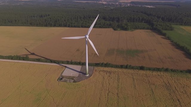 Wind Farm Turbine In Agricultural Fields On A Sunny Summer Day. Aerial Flying Forward