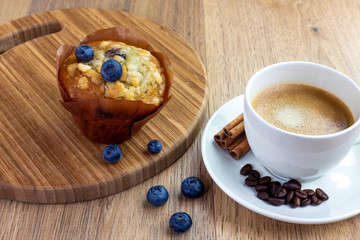 blueberry muffin with cup of cinnamon coffee on wooden table

