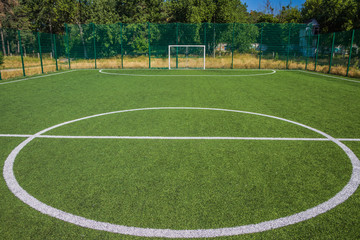 Soccer field with artificial green grass near the school. Amateur football field. Sunny summer day