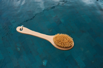A natural bristle brush rests on the water in the pool. Zero waste concept.