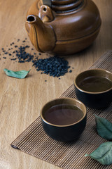 Asian tea set and tea leaves on a wooden table.