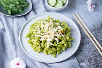 Recipe for durum wheat pasta with cheese, pesto and arugula on a gray background. Healthy vegetarian lunch without meat. Balanced proper nutrition for weight loss and diet. Healthy lifestyle.