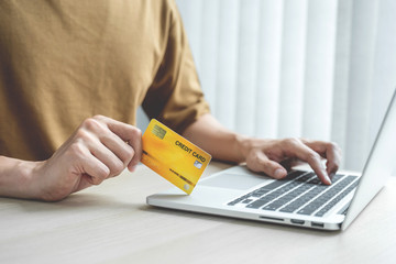 Businessman hand hold credit card to online shopping on laptop computer from home, payment e-commerce, internet banking, spending money