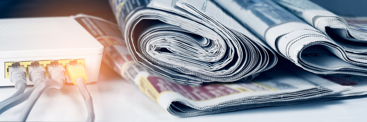 Panoramic image of a stack of newspapers and a wi-fi router, media concept.