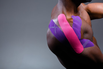 Close-up of an African American shoulder. Kinesio tape on the shoulder joint