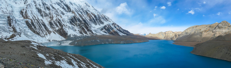 Fototapeta na wymiar A panoramic view on turquoise colored Tilicho lake in Himalayas, Manang region in Nepal. The world's highest altitude lake (4949m). Snow capped mountains around. Calm surface of the lake. Serenity