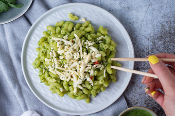 Recipe for durum wheat pasta with cheese, pesto and arugula on a gray background. Healthy vegetarian lunch without meat. Balanced proper nutrition for weight loss and diet.