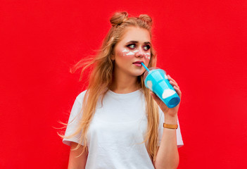 Beautiful long-haired blonde girl drinking cloud cocktail with smile on red background