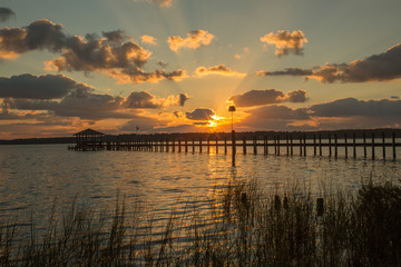 A pier stretching out in Mobile Bay at sunset, at Fairhope Alabama. - obrazy, fototapety, plakaty
