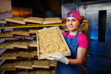 Make the noodles. Pasta factory. Spaghetti production. Raw pasta. Worker with a box of pasta. Girl works in the production of pasta