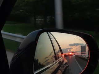Fototapeta na wymiar car rear view mirror looking back bridge sunset sky driving riding vehicle